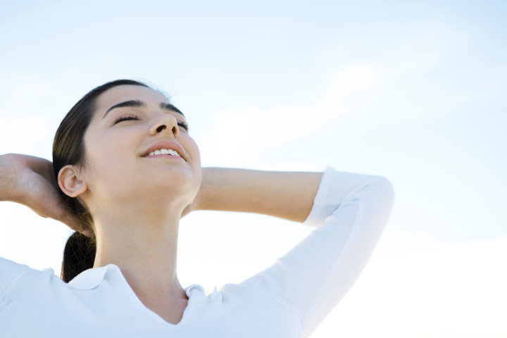 Woman with eyes closed, hands behind head